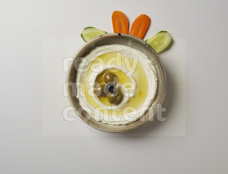 Lebnah garnished with whole olives in a grey pottery plate on a white background