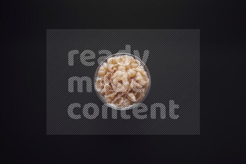Snails pasta in a glass bowl on black background