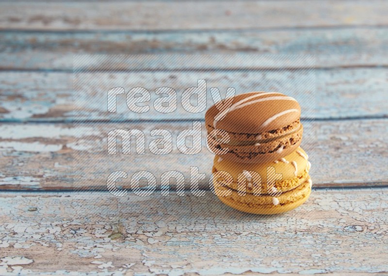 45º Shot of of two assorted Brown Irish Cream, and Yellow Piña Colada macarons on light blue background