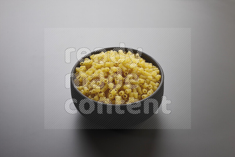Small rings pasta in a pottery bowl on grey background