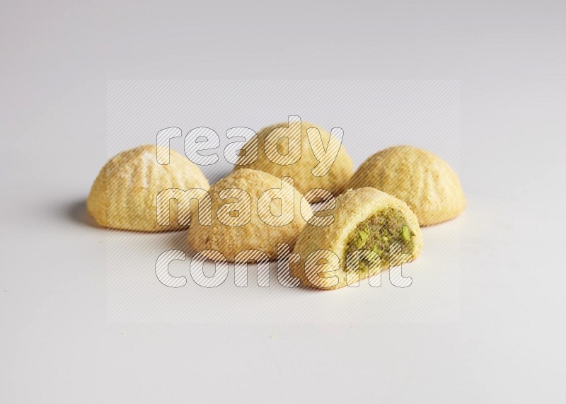 Five Pieces of Maamoul filled with pistachio  paste one of them is cut direct on white background