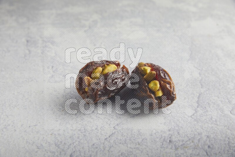 two pistachio stuffed madjoul date on a light grey background