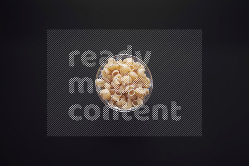 Pipe pasta in a glass bowl on black background