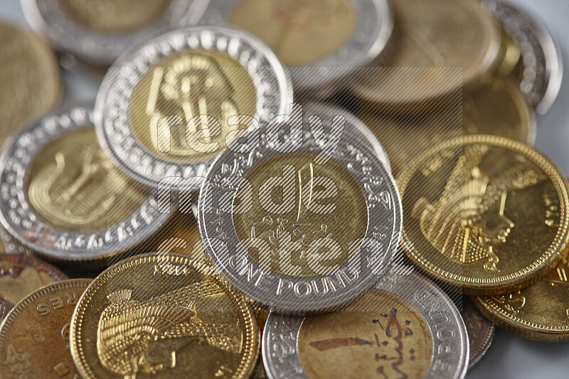A close-up of scattered mixed Egyptian coins such as One pound, 50 and 25 piasters on grey background