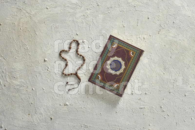 Quran with a prayer beads on white background