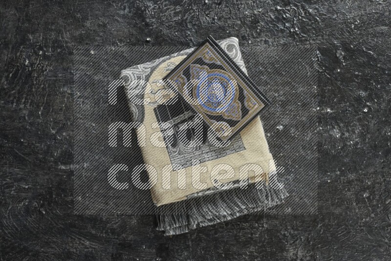 سجادة صلاة مطوية بعناصر مختلفة مثل القرآن الكريم وسبحة الصلاة على خلفية سوداء