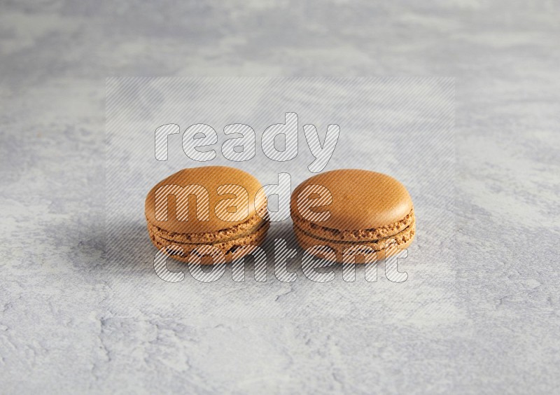 45º Shot of two Brown Maple Taffy macarons  on white  marble background