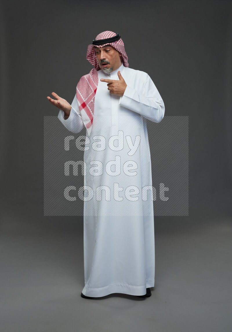 Saudi man with shomag Standing Interacting with the camera on gray background