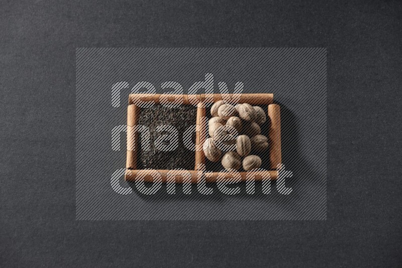 مربعان من أعواد القرفة ممتلئان بالشاي وجوزة الطيب علي خلفية سوداء