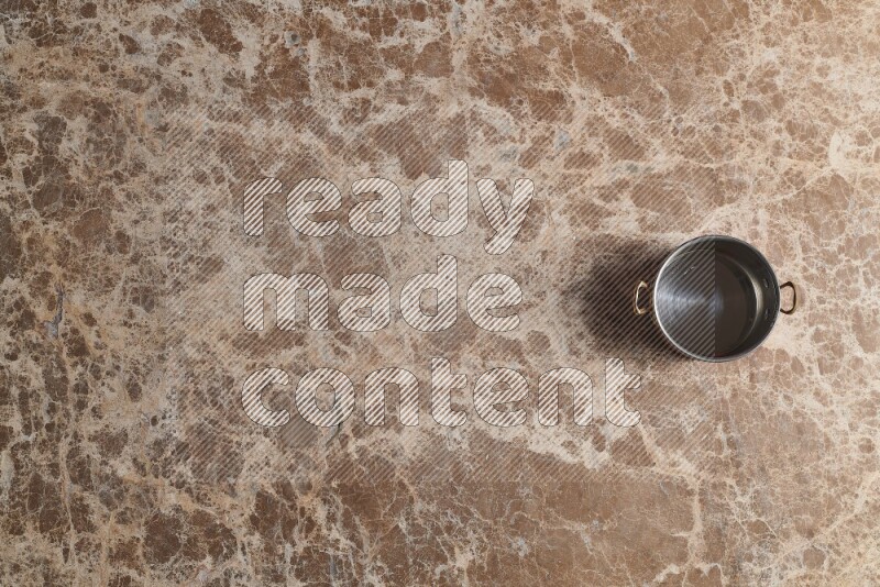A small copper pot on beige marble background
