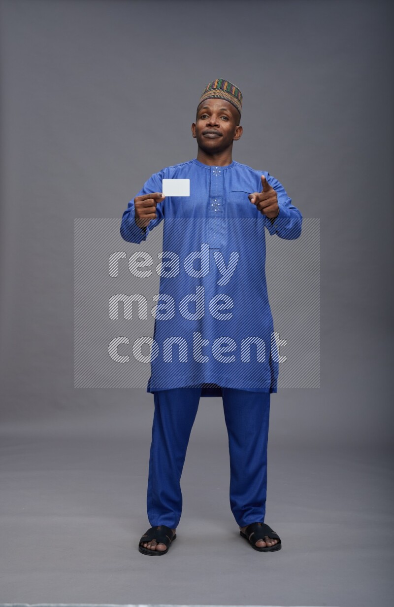 Man wearing Nigerian outfit standing holding ATM card on gray background