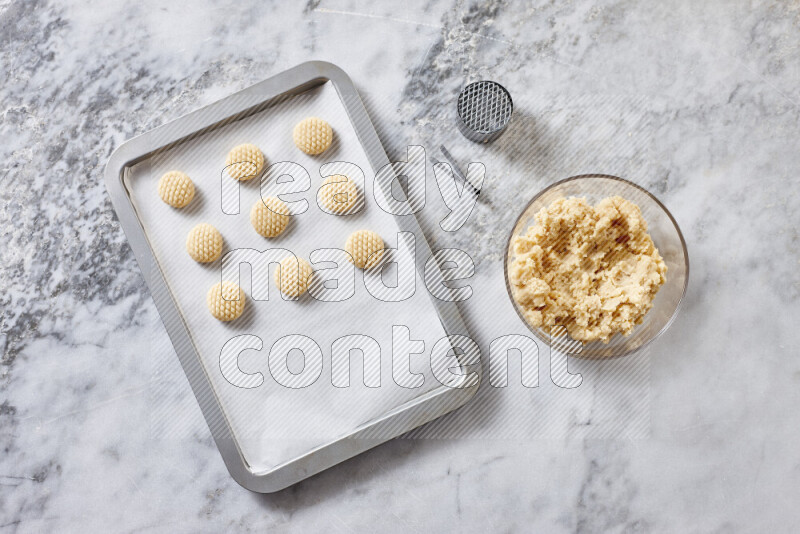 كحك خطوة بخطوة بمكوناته سمن، سكر، دقيق، سمسم، خميرة، ماء ونكهة الكحك على خلفية رخام رمادي