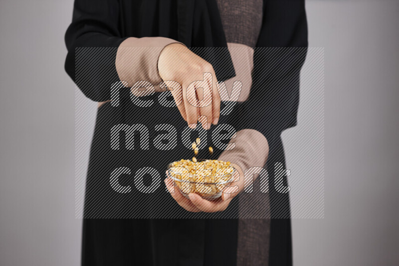 Woman in abaya holding different kinds of legumes in different positions
