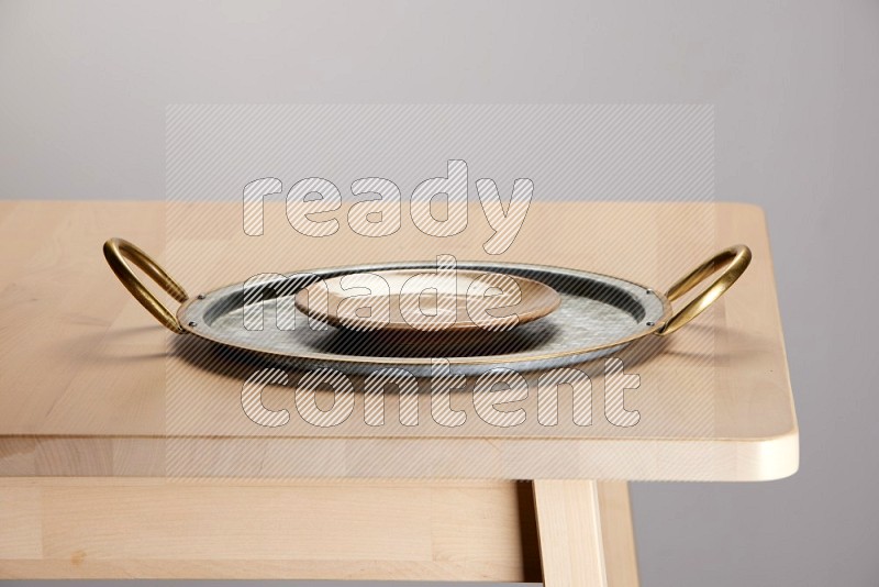 multicolored plate placed on a rounded stainless steel tray with golden handels on the edge of wooden table