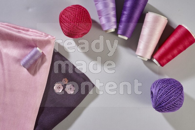 أقمشة متعددة الألوان مع لوازم الخياطة على خلفية رمادية