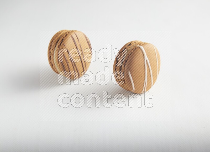 45º Shot of of two assorted Brown Irish Cream, and light brown  Almond Cream macarons on white background