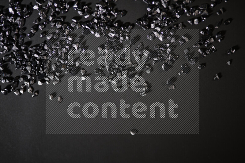 قطع زجاجية سوداء لامعة متناثرة على خلفية سوداء