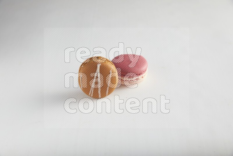 45º Shot of of two assorted Brown Irish Cream, and Pink Litchi Raspberry macarons on white background