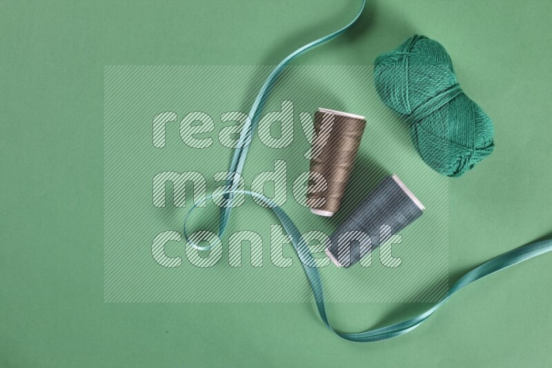 A green collection of sewing and tailoring tools arranged on a green background
