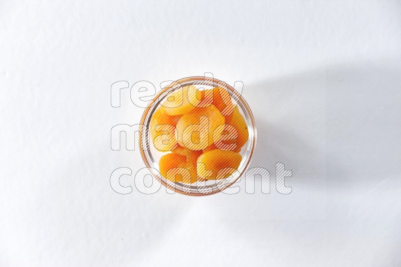 A glass bowl full of dried apricots on a white background in different angles