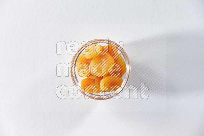 A glass bowl full of dried apricots on a white background in different angles