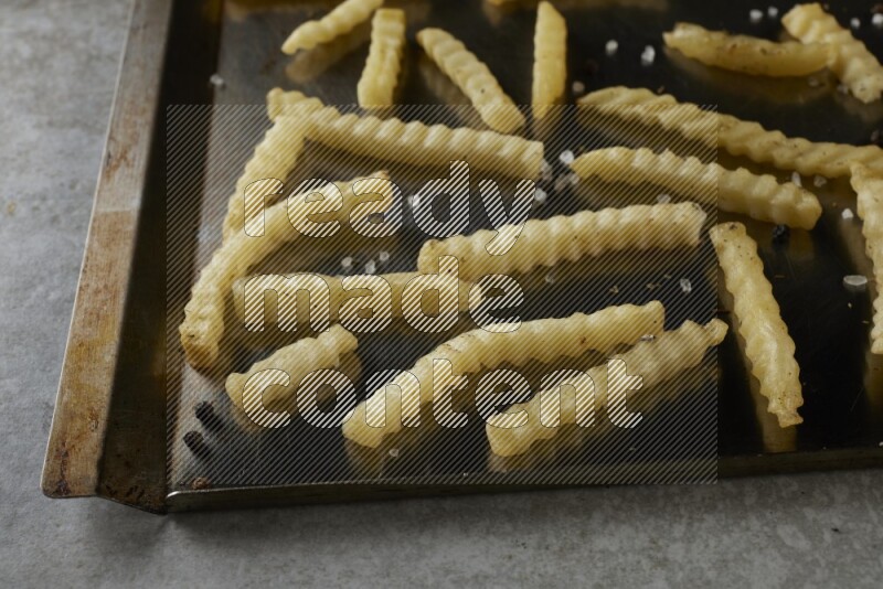 crinkle fries in a black stainless steel rectangle tray on grey textured counter top