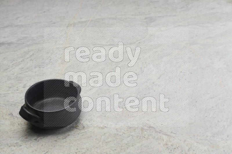 A black pottery bowl on grey marble background