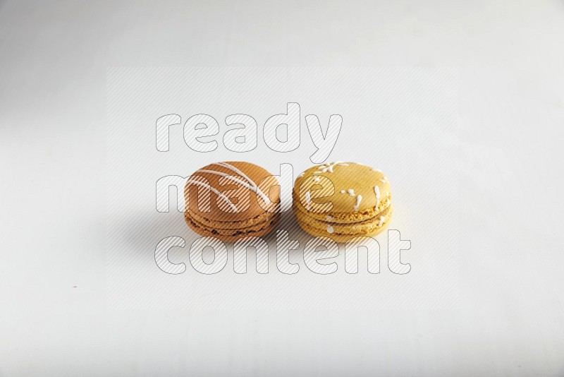 45º Shot of of two assorted Brown Irish Cream, and Yellow Piña Colada macarons on white background