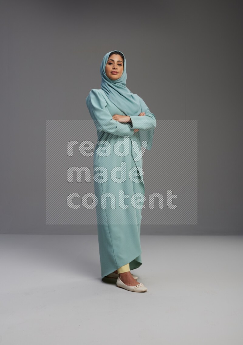 Saudi Woman wearing Abaya standing with crossed arms on Gray background