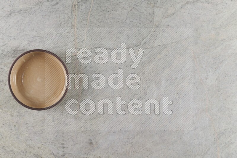 وعاء فرن فخاري باللون البيج على خلفية من الرخام الرمادي