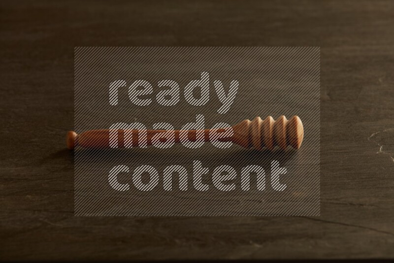 Wooden honey dipper on black slate background