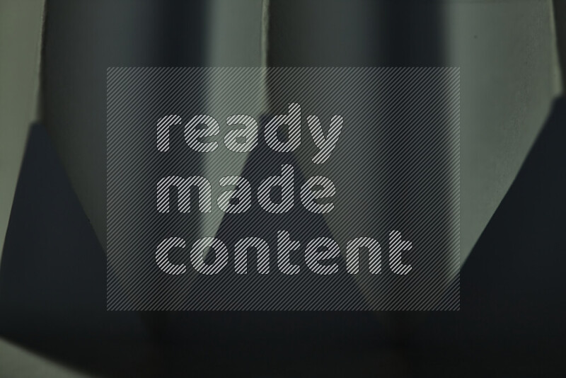 A close-up abstract image showing sharp geometric paper folds in green gradients