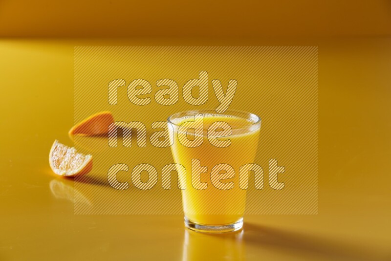 glass of orange juice on yellow background