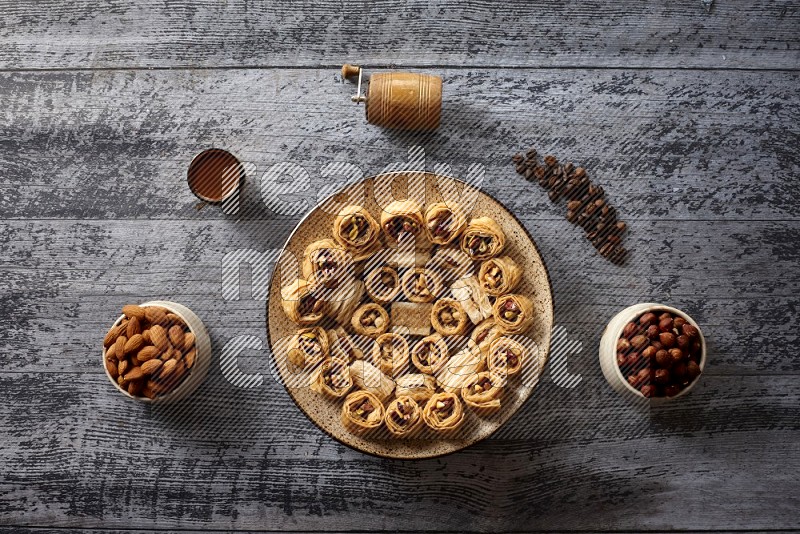 حلويات شرقية في صحن فخاري مع المكسرات والقهوة والعسل علي خلفية خشبية