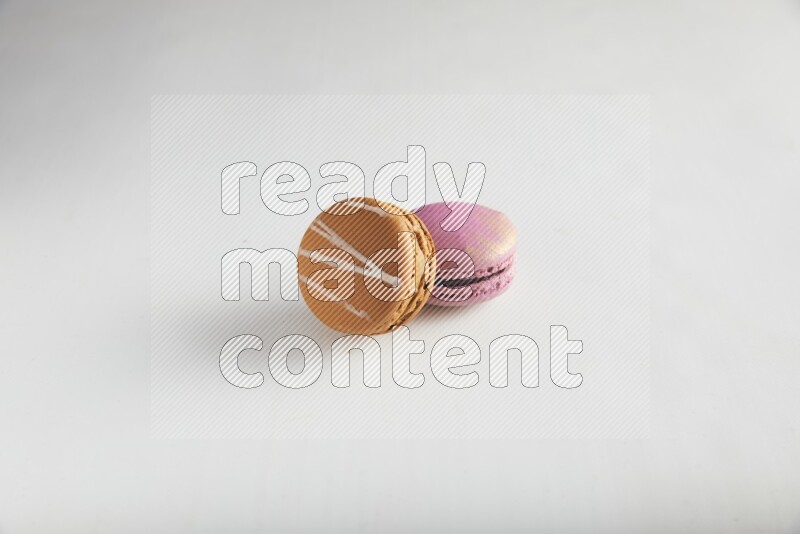 45º Shot of of two assorted Brown Irish Cream, and Purple Strawberry macarons on white background