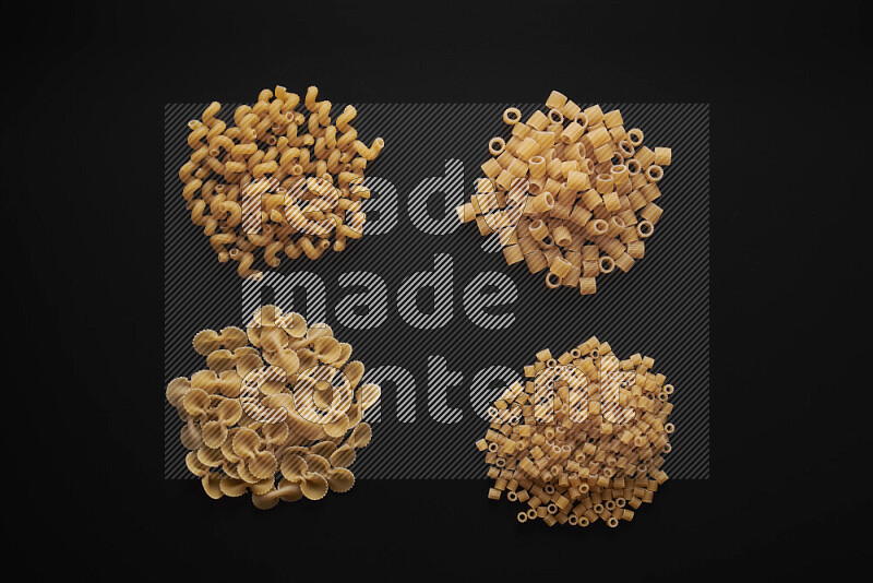 Different pasta types in bunches on black background