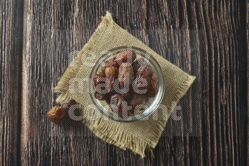Dates in different bowls (wooden, pottery and glass) on wooden background