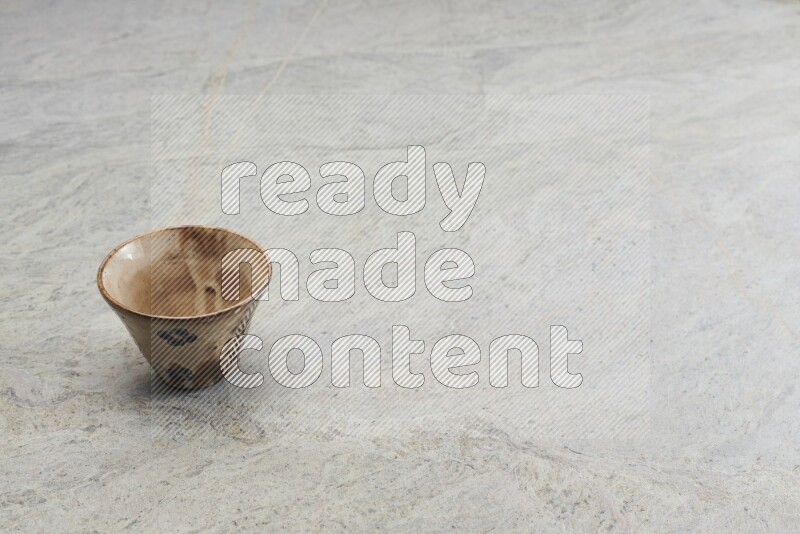 كأس فخاري متعدد الألوان على خلفية من الرخام الرمادي