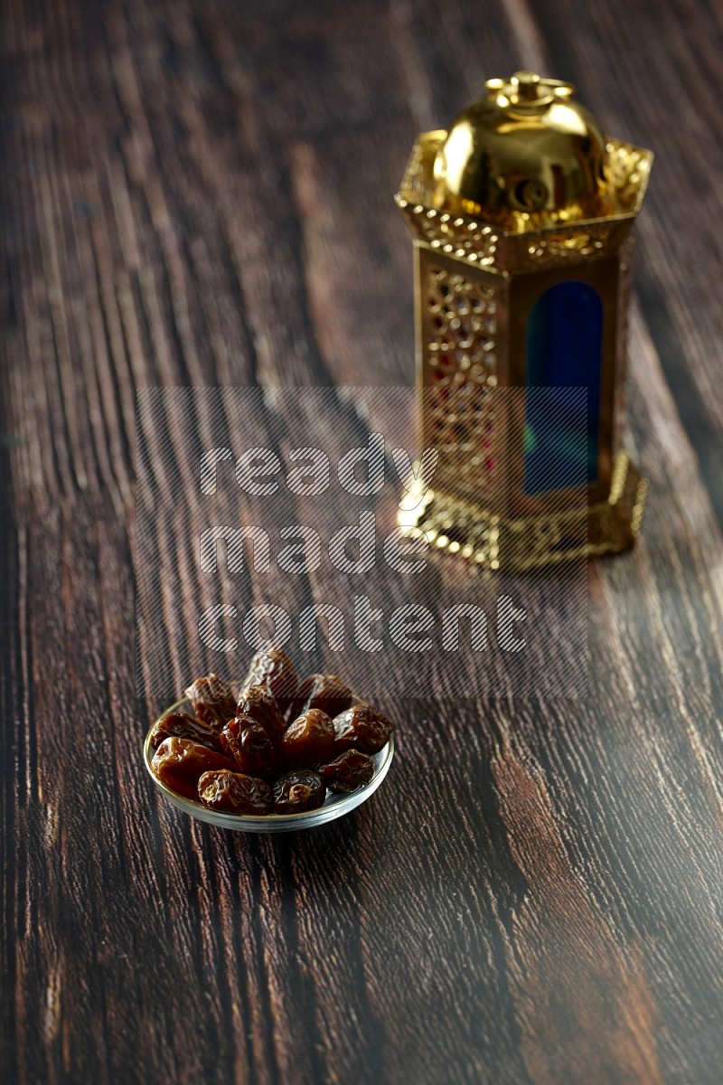 A golden lantern with different drinks, dates, nuts, prayer beads and quran on brown wooden background