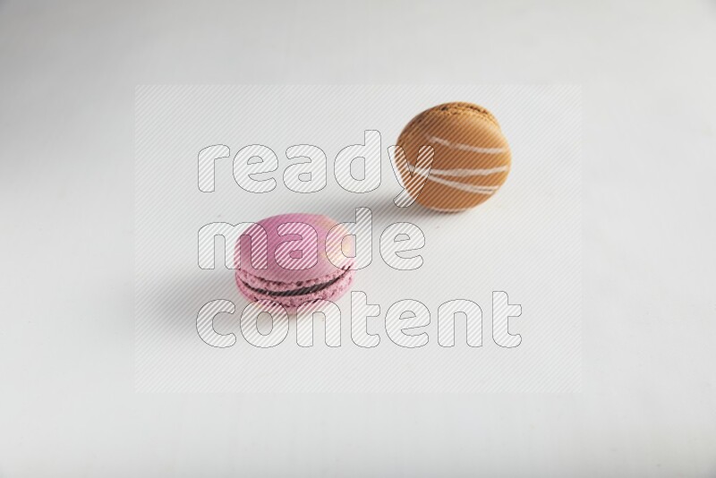 45º Shot of of two assorted Brown Irish Cream, and Purple Strawberry macarons on white background