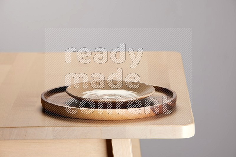 multi-colored pottery Plate placed on a light colored wooden tray on the edge of wooden table