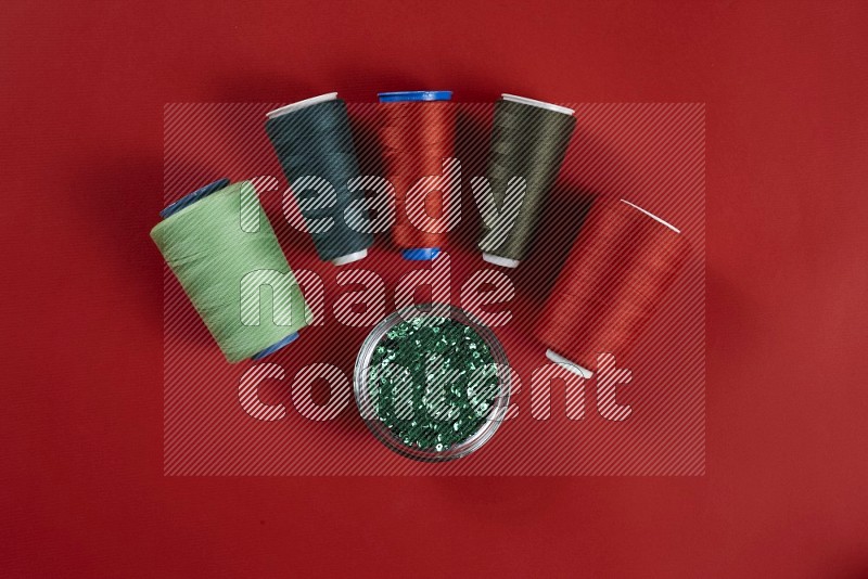 Green sewing supplies on red background