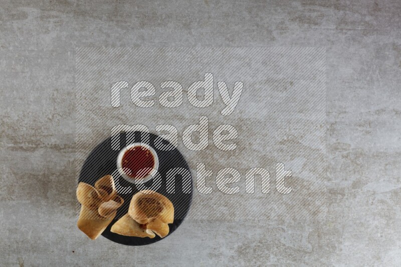 wonton cups with soy sauce ramkin on circle slate on grey textured counter top