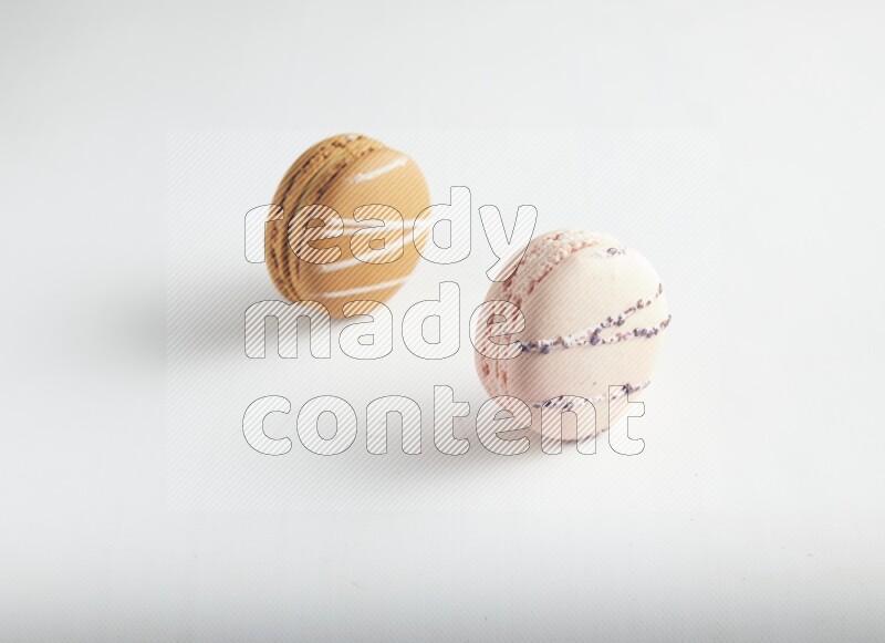 45º Shot of of two assorted Brown Irish Cream, and pink orange blossom macarons on white background