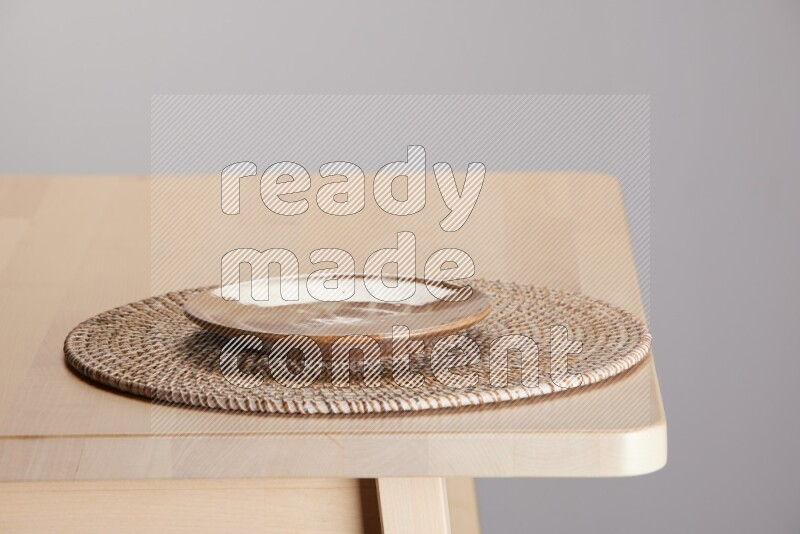 multi-colored pottery Plate placed on a big light colored straw placemat on the edge of wooden table