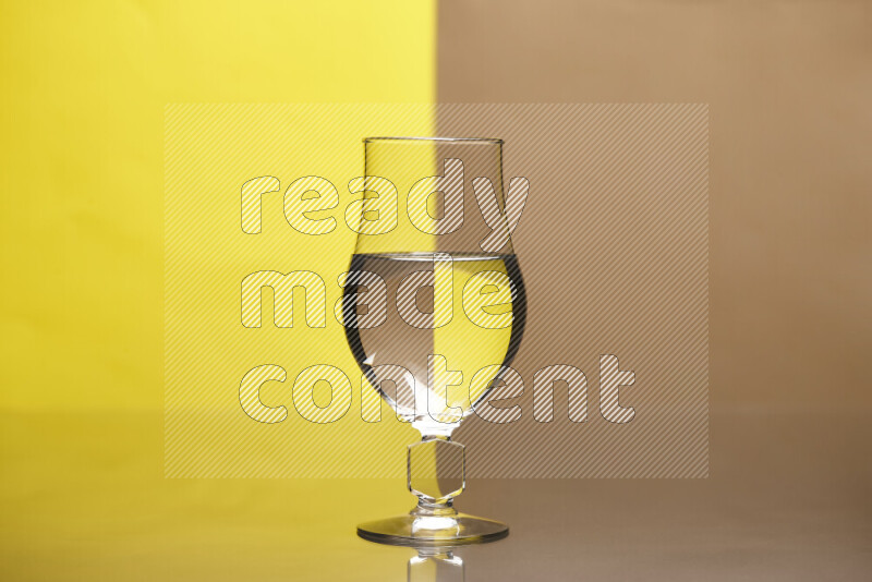 The image features a clear glassware filled with water, set against yellow and beige background