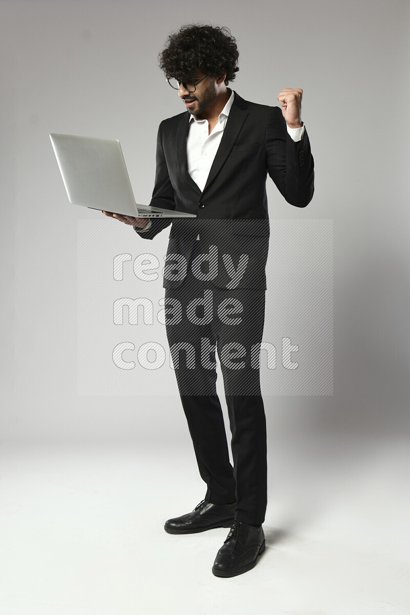 A man wearing formal standing and working on a laptop on white background