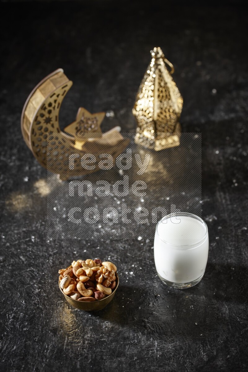 مكسرات في وعاء معدني مع السوبيا بجانب فوانيس ذهبية علي خلفية سوداء