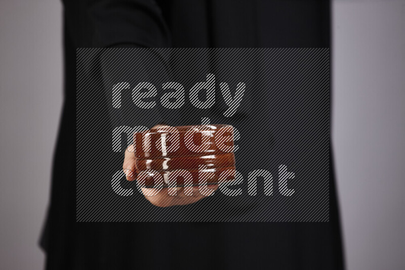 A woman in black abaya holding different pottery essentials in different positions