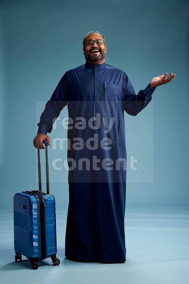 Saudi Man without shimag Standing pulling travel bag on blue background